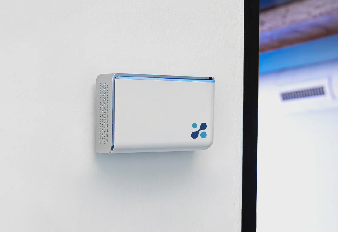 Aethair IAQ monitoring the indoor air quality of a room, mounted next to a QR code that provides real-time data access to anyone who scans it.