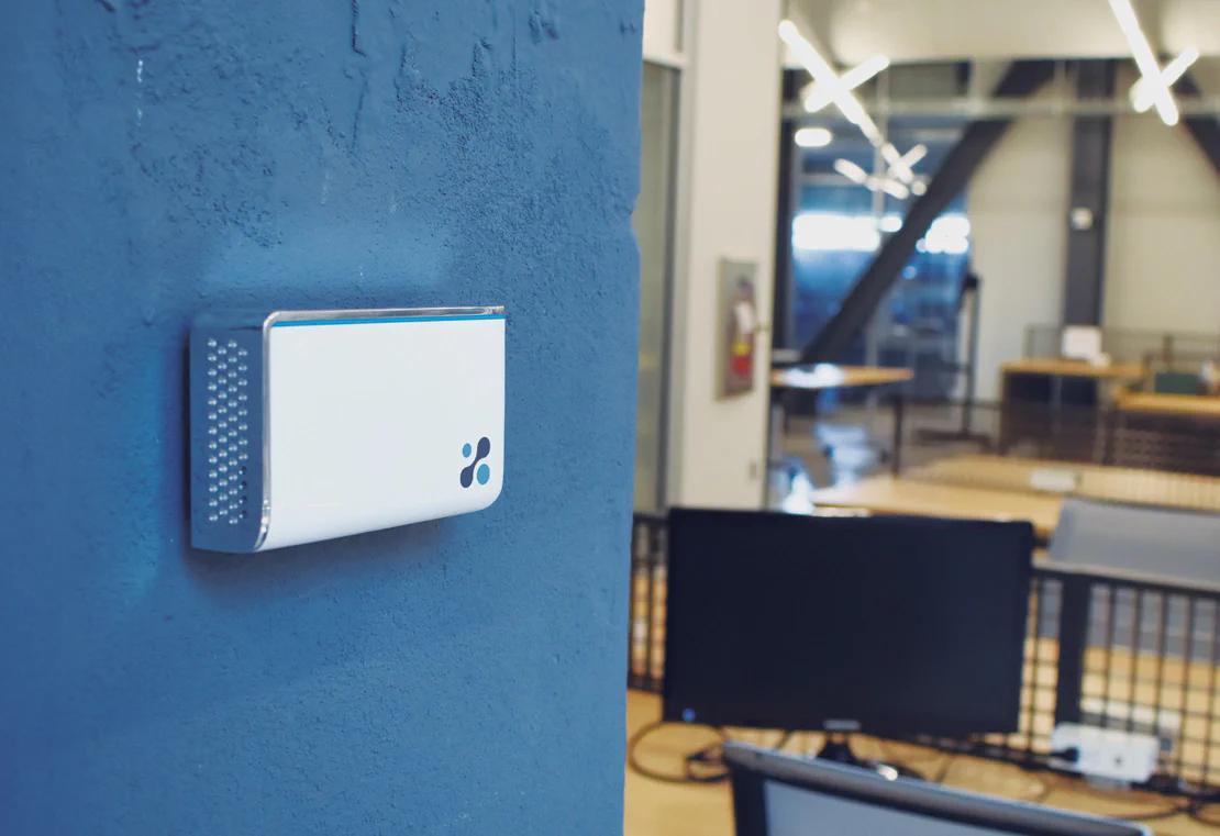 Aethair IAQ mounted to a stone wall inside a modern workspace.