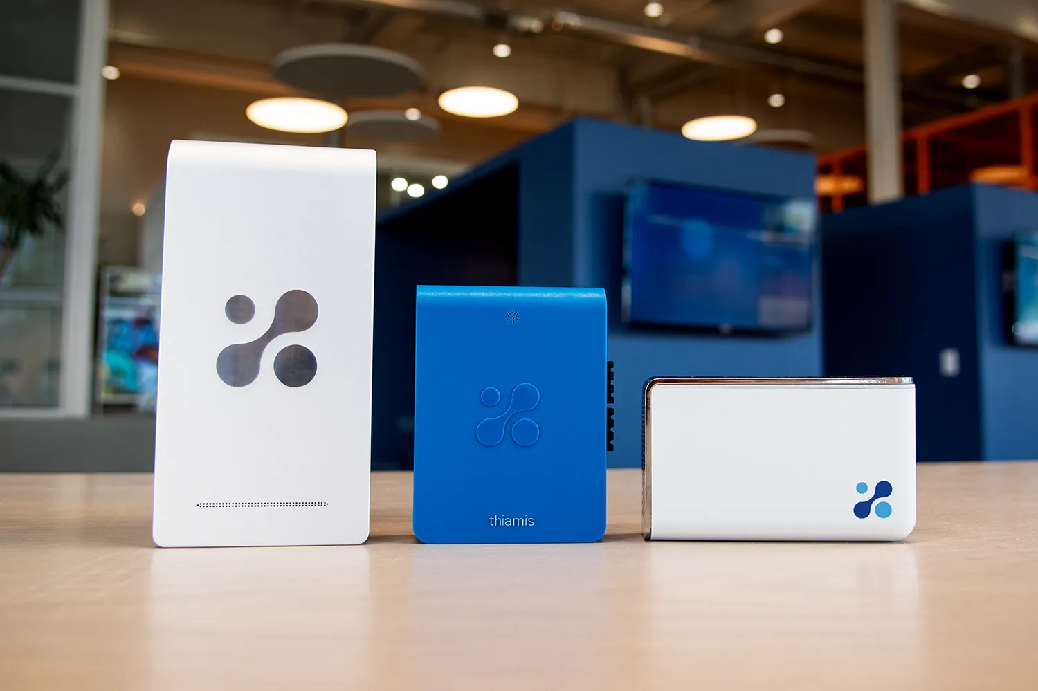 Aethair PRO, Thiamis, and Aethair IAQ side by side on a table in an office