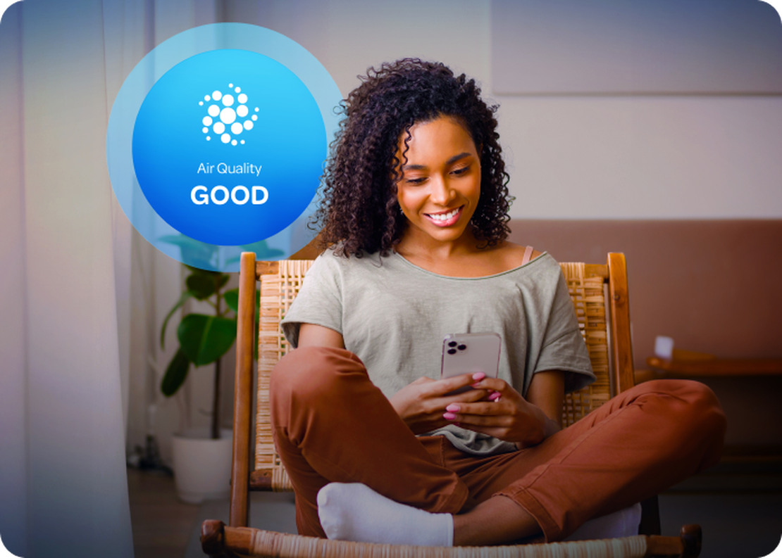 Woman reviewing air quality on the Aethair mobile app with Aethair “Good” air quality status displayed behind her.