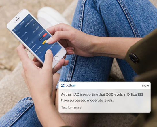 Woman setting up alerts on the Aethair mobile app with a push notification displayed over the image.