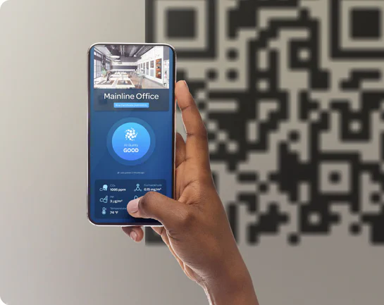 Hand holding a mobile phone scanning a QR code to view real-time air quality status.