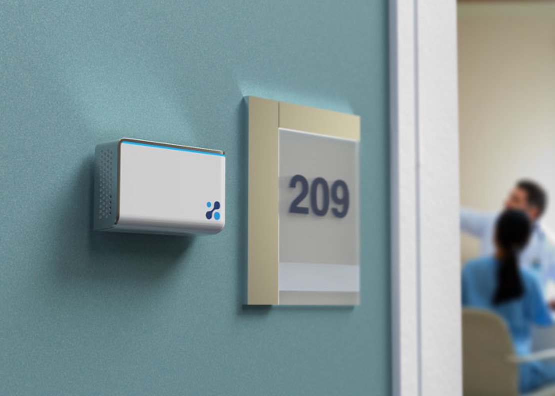Aethair IAQ mounted next to a room number with doctors talking in the background.