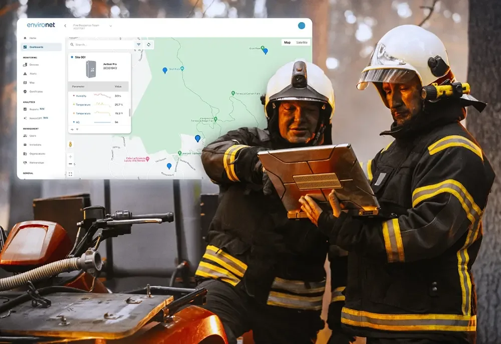 Two firefighters reviewing Aethair PRO readings on a rugged laptop, with the Environet station map beside them.