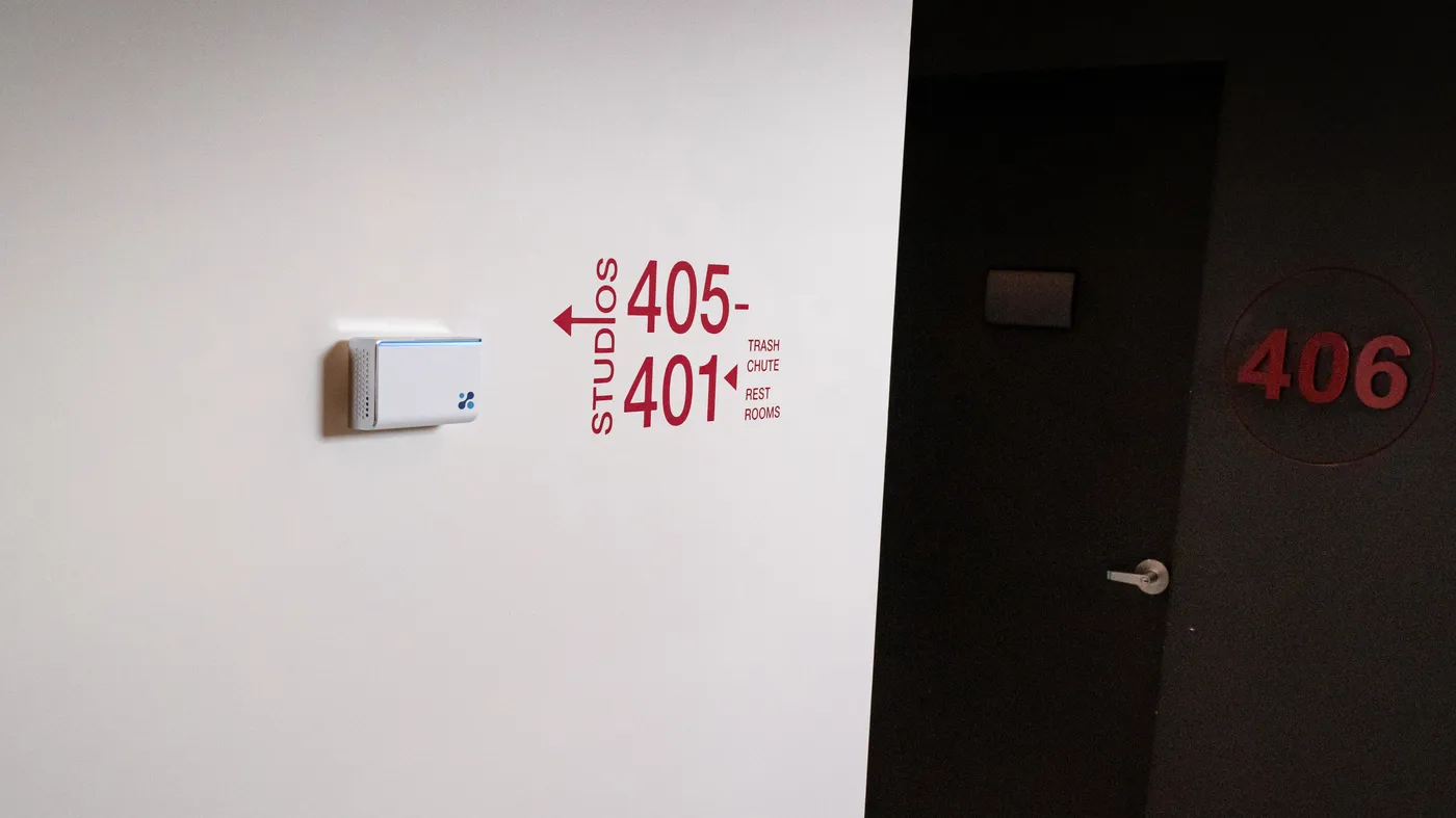 Aethair IAQ on a corridor wall beside a direction sign for studios 401 to 405.