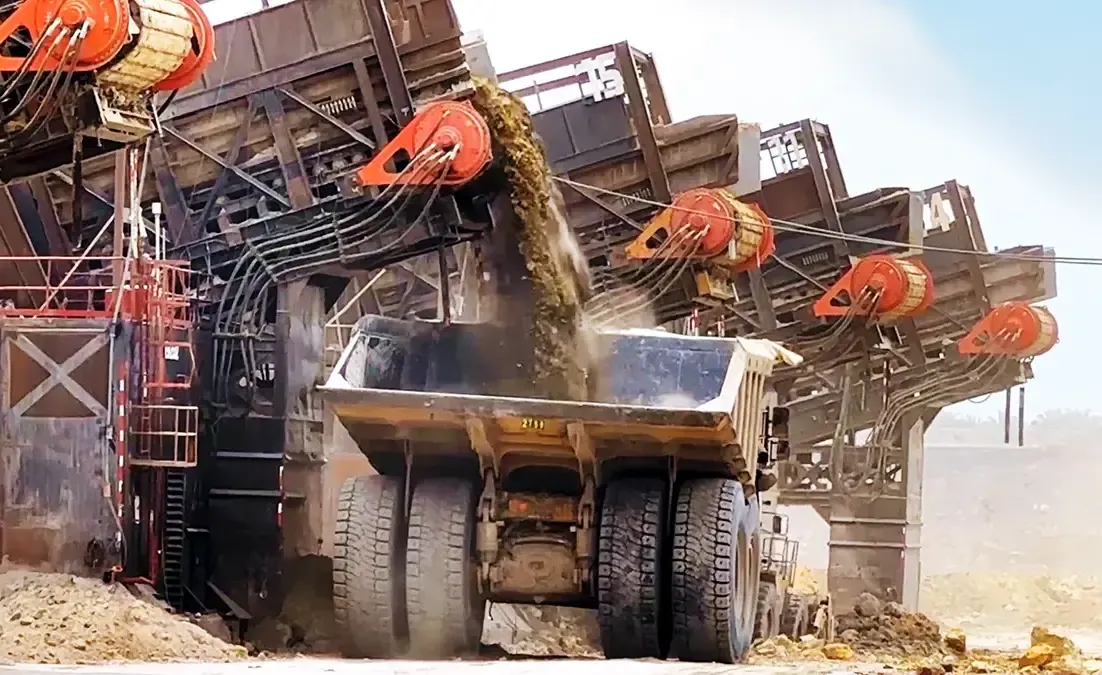 A mining excavator loading earth into a large haul truck at an open-pit mine.