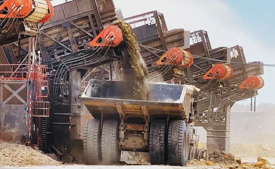 Mining equipment dumping dirt into a large dump truck.