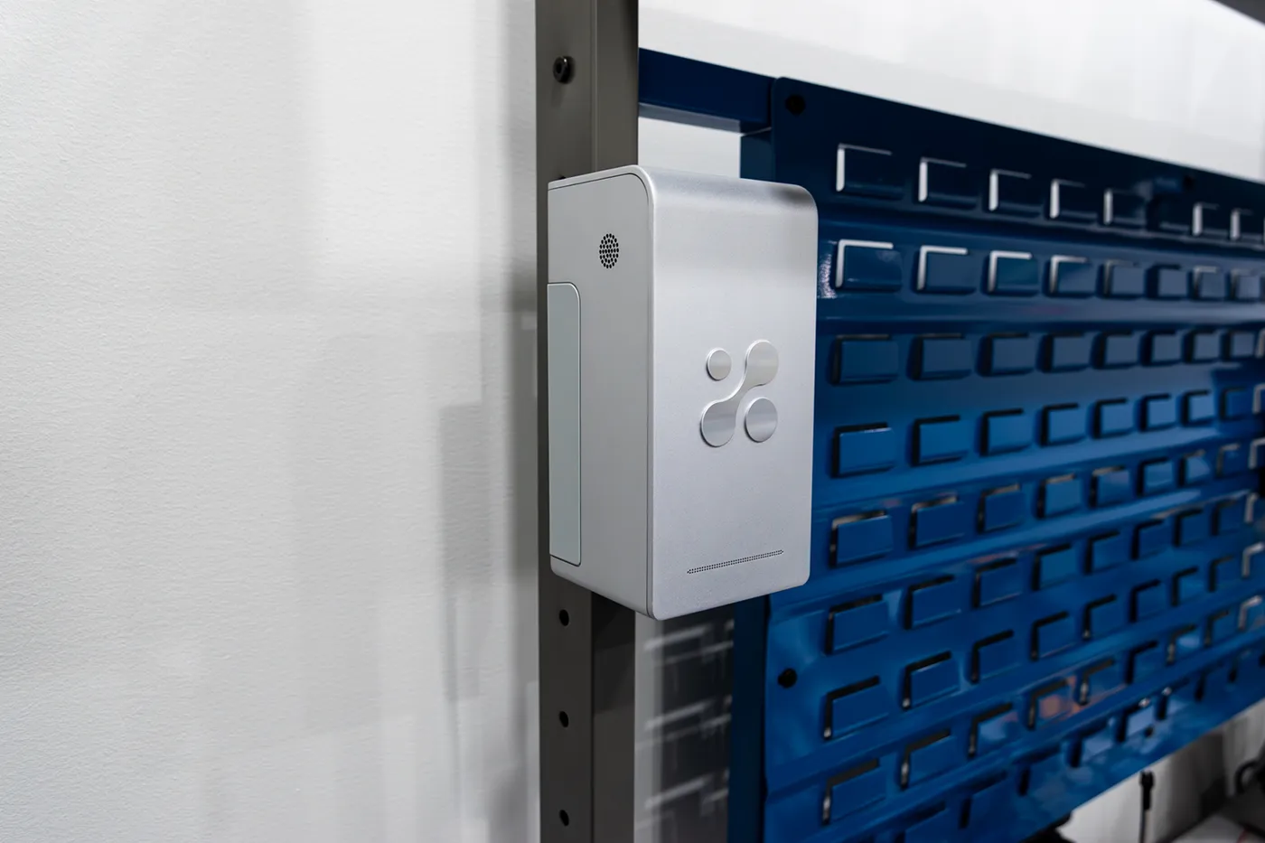 Aethair PRO mounted on a wall beside a blue perforated storage panel.