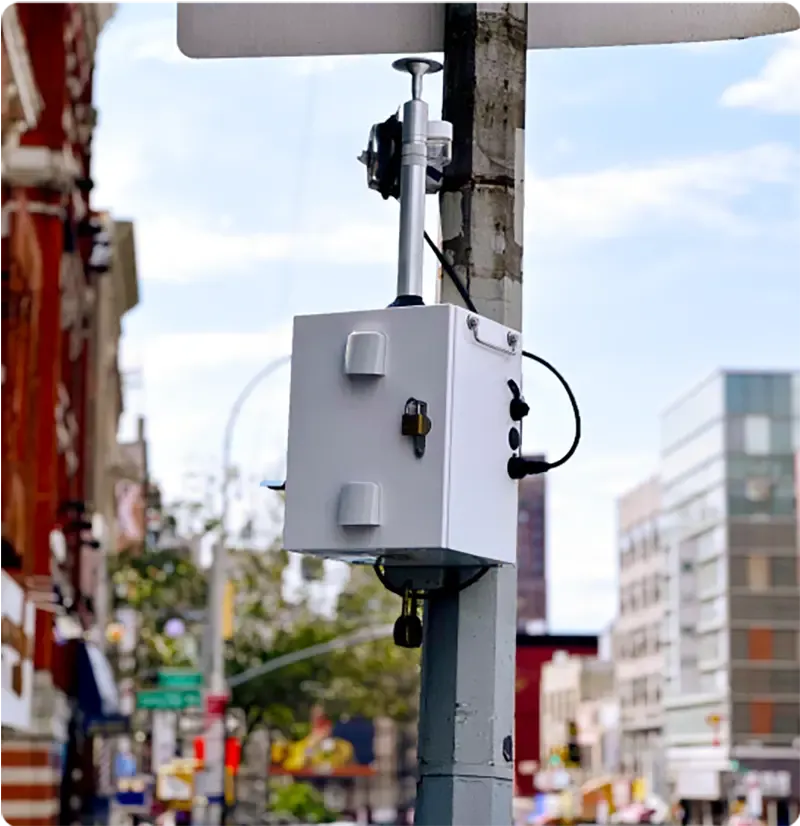 Thiamis in a weatherproof enclosure on a city street pole, with its sensor mounted above.