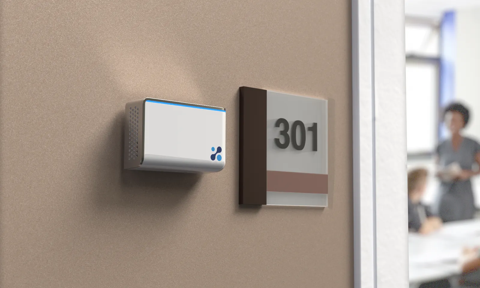 An Aethair IAQ air quality monitor on a corridor wall beside the sign for room 301, with people inside the room.