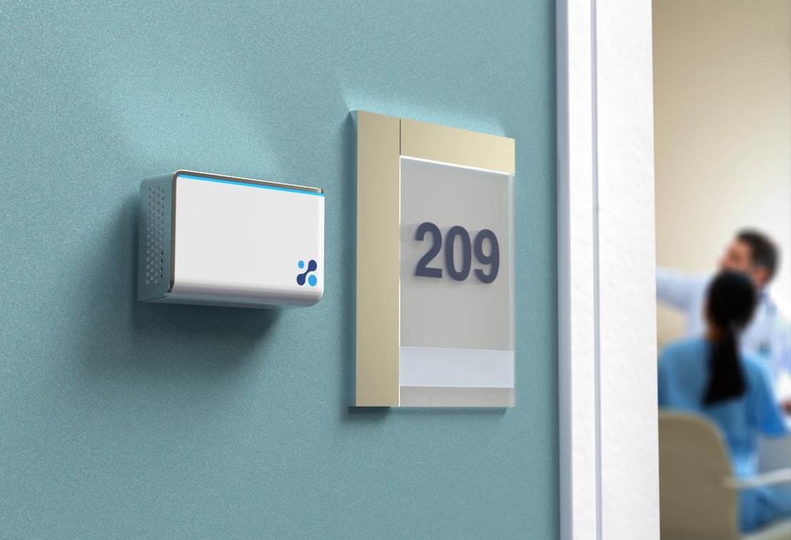 Aethair IAQ mounted next to a room number in a hallway with doctors talking in the background.