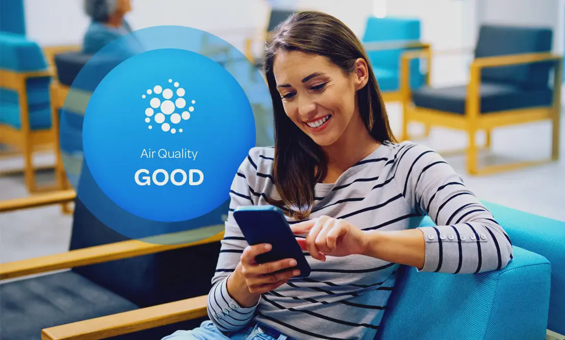 Aethair “Good” air quality status displayed behind a woman checking air quality data on her phone.