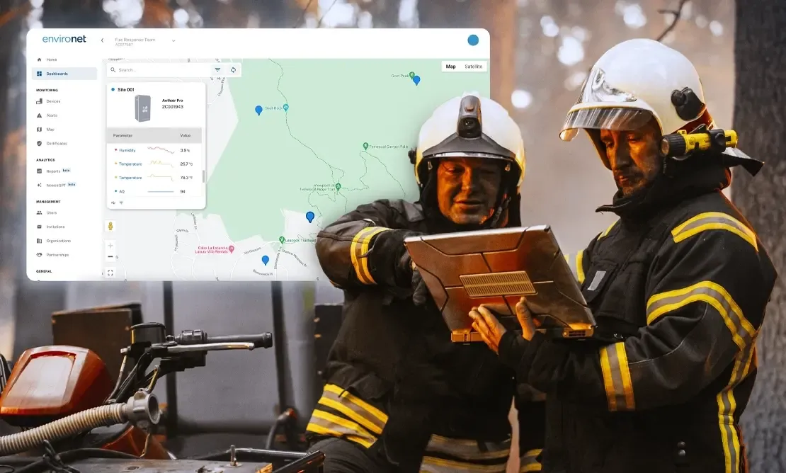 Two wildland firefighters reviewing Aethair PRO monitoring data on a laptop during a wildfire.