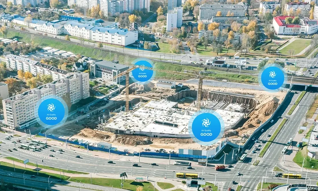 Aerial view of a construction site beside a highway, with "Good" air quality markers at the perimeter.