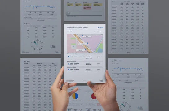 Hands holding an Aethair perimeter monitoring report with additional report pages in the background.
