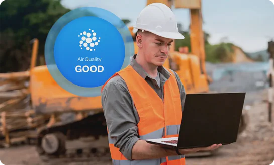 Aethair “Good” air quality status displayed behind a man using a laptop to review air quality data at a construction site.