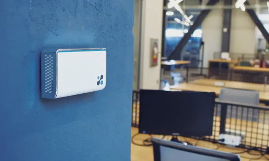 Aethair IAQ mounted on a concrete wall inside a modern workspace.
